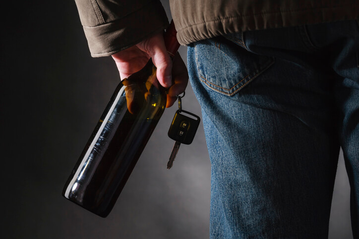 Man holding liquor bottle and car keys